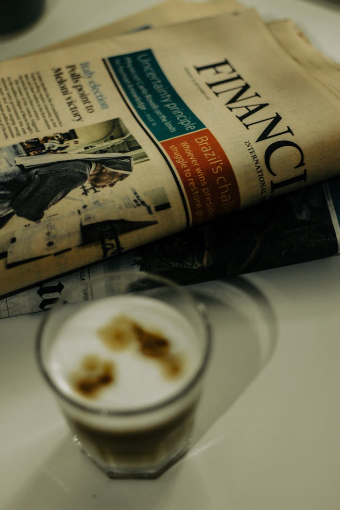 Close-up of a financial newspaper and coffee cup on a desk, ideal for finance themes.
